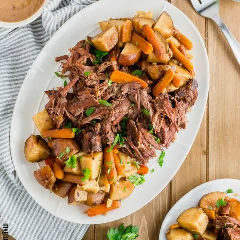 Gluten-free Pot Roast on a platter with a bowl of gravy