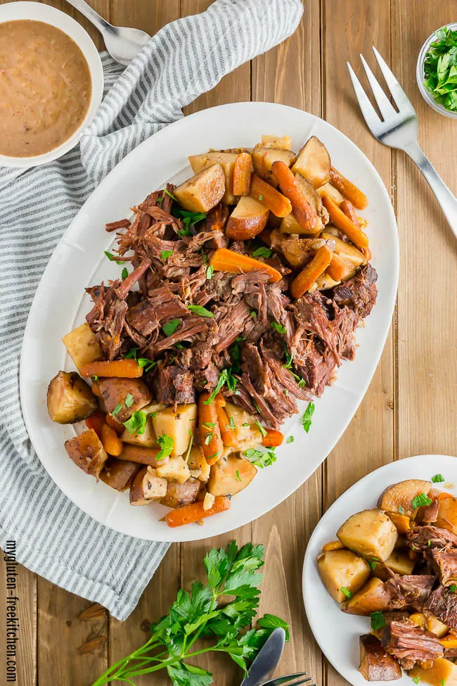 Gluten-free Pot Roast on a platter with a bowl of gravy