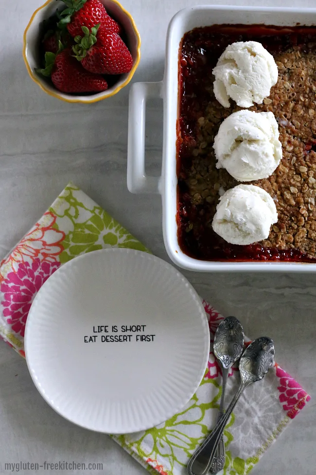 Gluten-free Rhubarb Strawberry Crisp in pan plus plate and bowl of strawberries