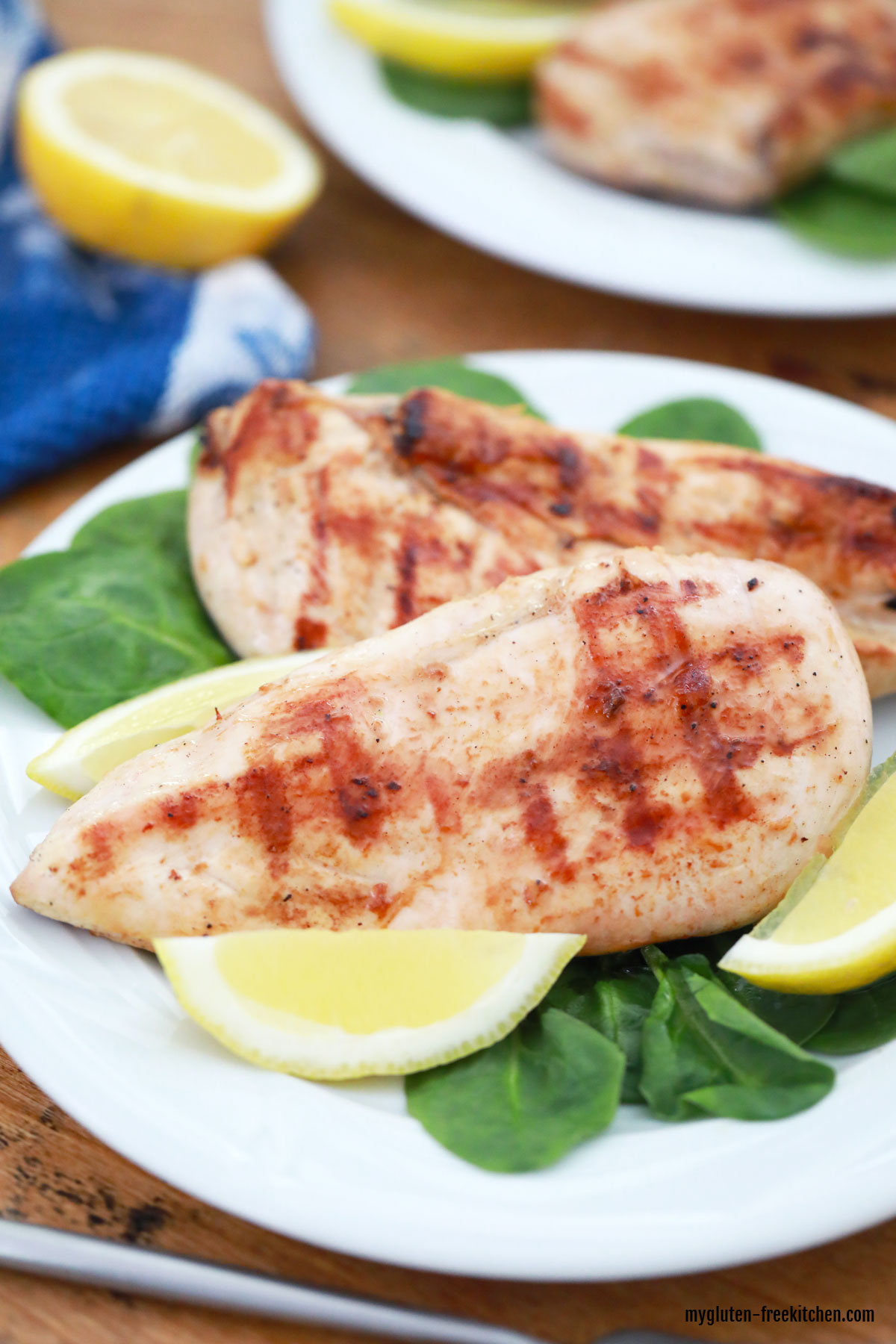 Gluten-free Lemon Chicken on white plate with spinach and lemon wedges