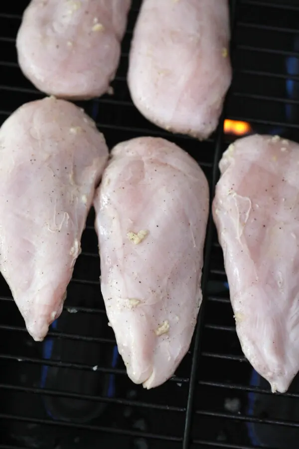 Raw marinated chicken breasts on grill