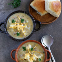2 bowls of gluten-free cheeseburger soup with spoons and rolls