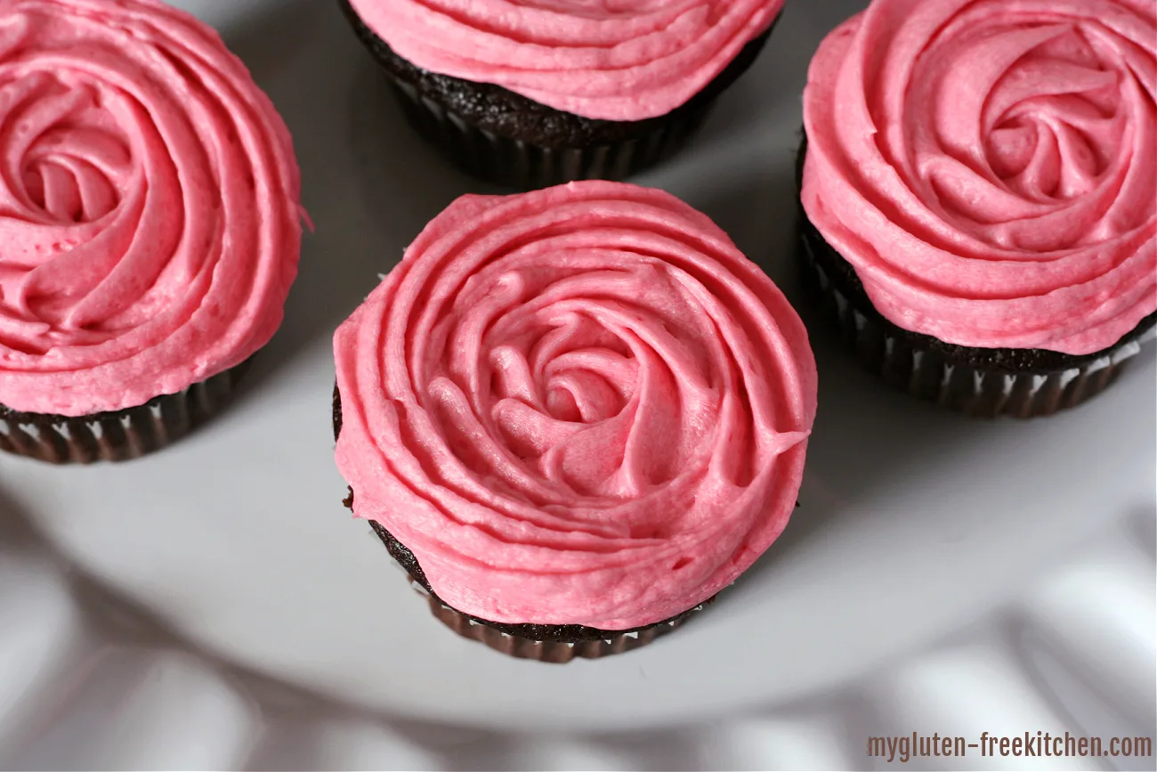 white plate with gluten-free chocolate cupcakes with swirled pink frosting