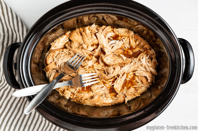 Crockpot with shredded chicken and two forks
