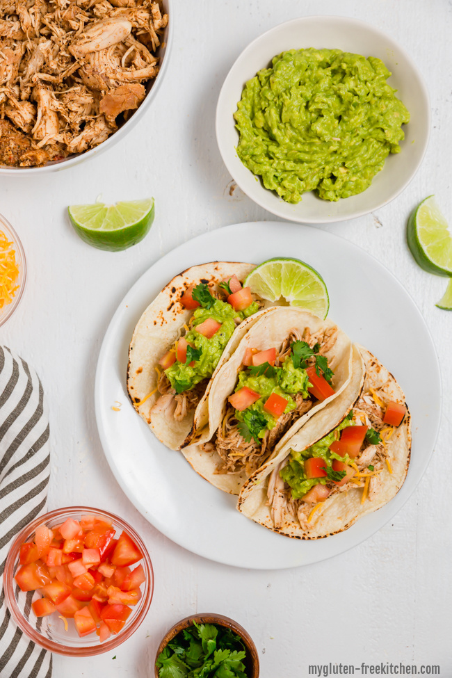 gluten-free chicken tacos on plate with toppings around it.