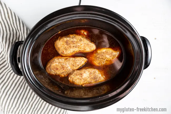 Crockpot with chicken, chicken broth, and seasonings