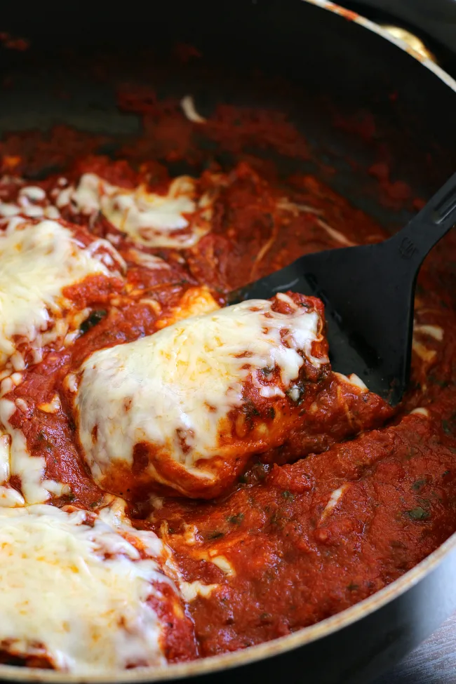 Skillet with chicken and spaghetti sauce and melted cheese for skillet chicken parmesan