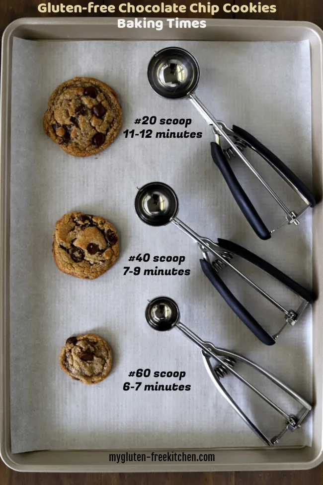 Three different sizes of gluten-free chocolate chip cookies on cookie sheet with three cookie scoops beside them