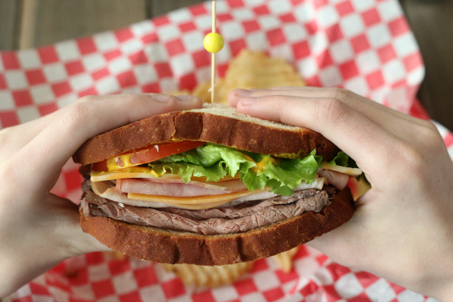 Have a bite of a gluten-free triple meat sandwich on full size Canyon Bakehouse Heritage bread.