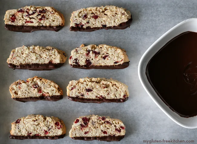 Gluten-free Chocolate Dipped Almond Biscotti sliced next to a bowl of melted chocolate