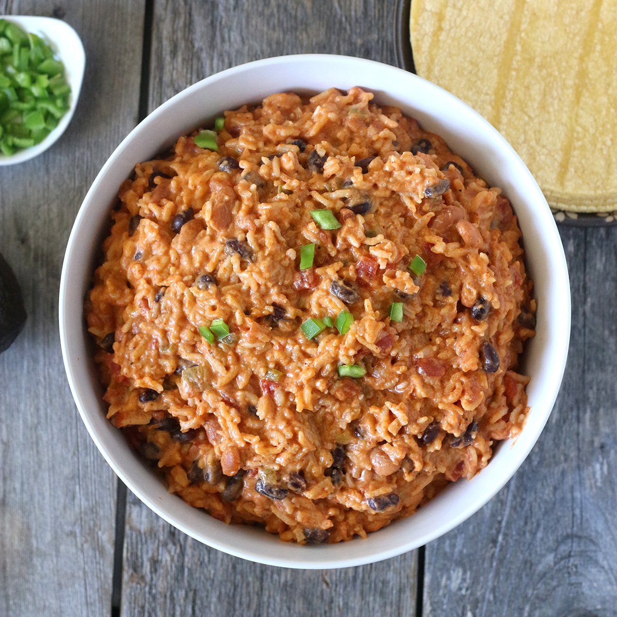 overhead image of reddish brown mixture of rice with black beans and some green scallions on top