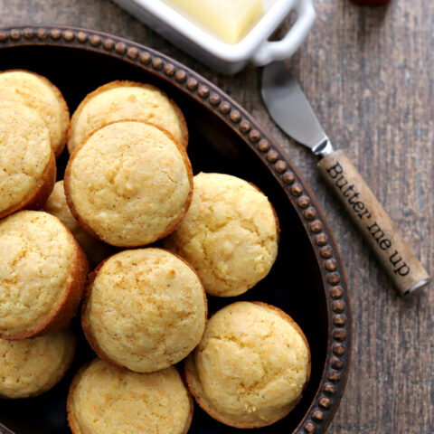 Gluten-free Corn Muffins in bowl with knife and butter