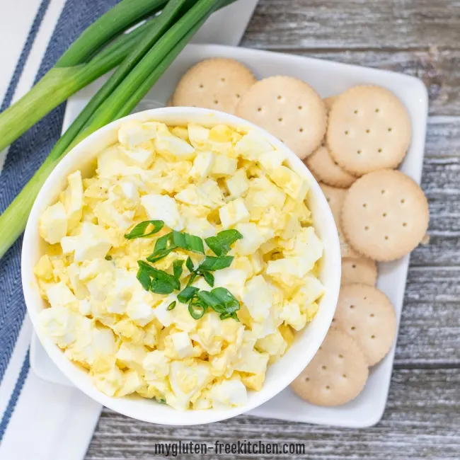 bowl of egg salad next to crackers