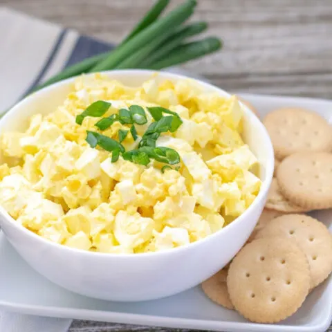 Bowl of egg salad with crackers next to it