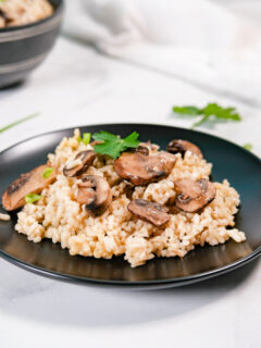 black plate with gluten-free risotto with mushrooms.