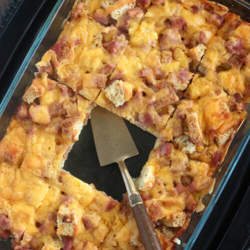 closeup overhead image of gluten free breakfast casserole in glass casserole dish with metal spatula